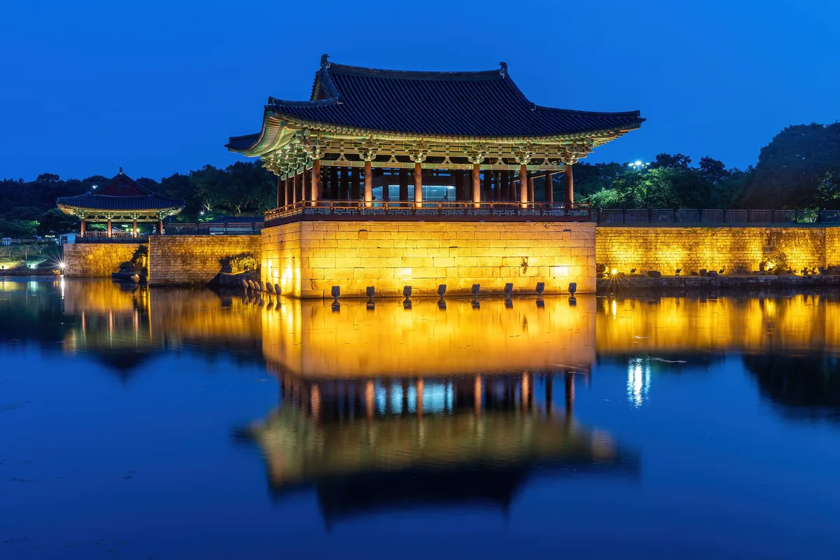 해 질 녘 불 켜진 경주 동궁과 월지 누각이 연못에 비친 모습